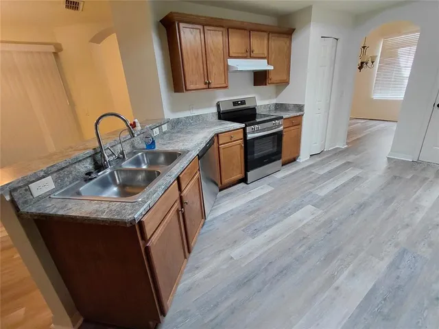 a kitchen with granite countertop a sink wooden floor and stainless steel appliances
