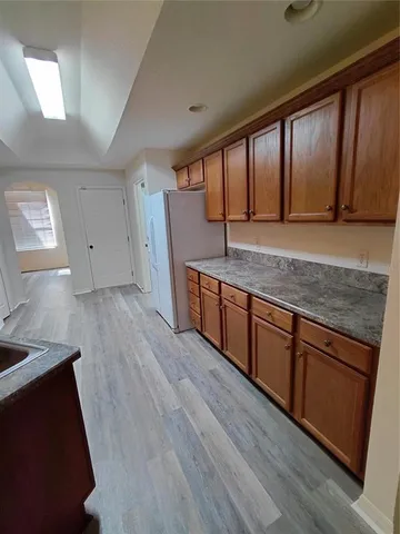 a kitchen with stainless steel appliances granite countertop wooden cabinets a sink and dishwasher a refrigerator with wooden floor