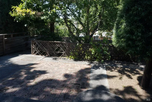 a view of backyard with wooden fence and trees