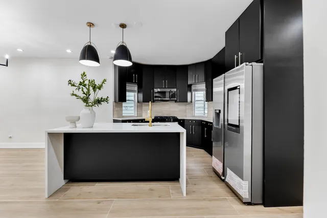 a kitchen with kitchen island stainless steel appliances a sink cabinets and wooden floor