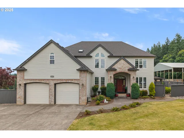 a view of a white house next to a yard with potted plants