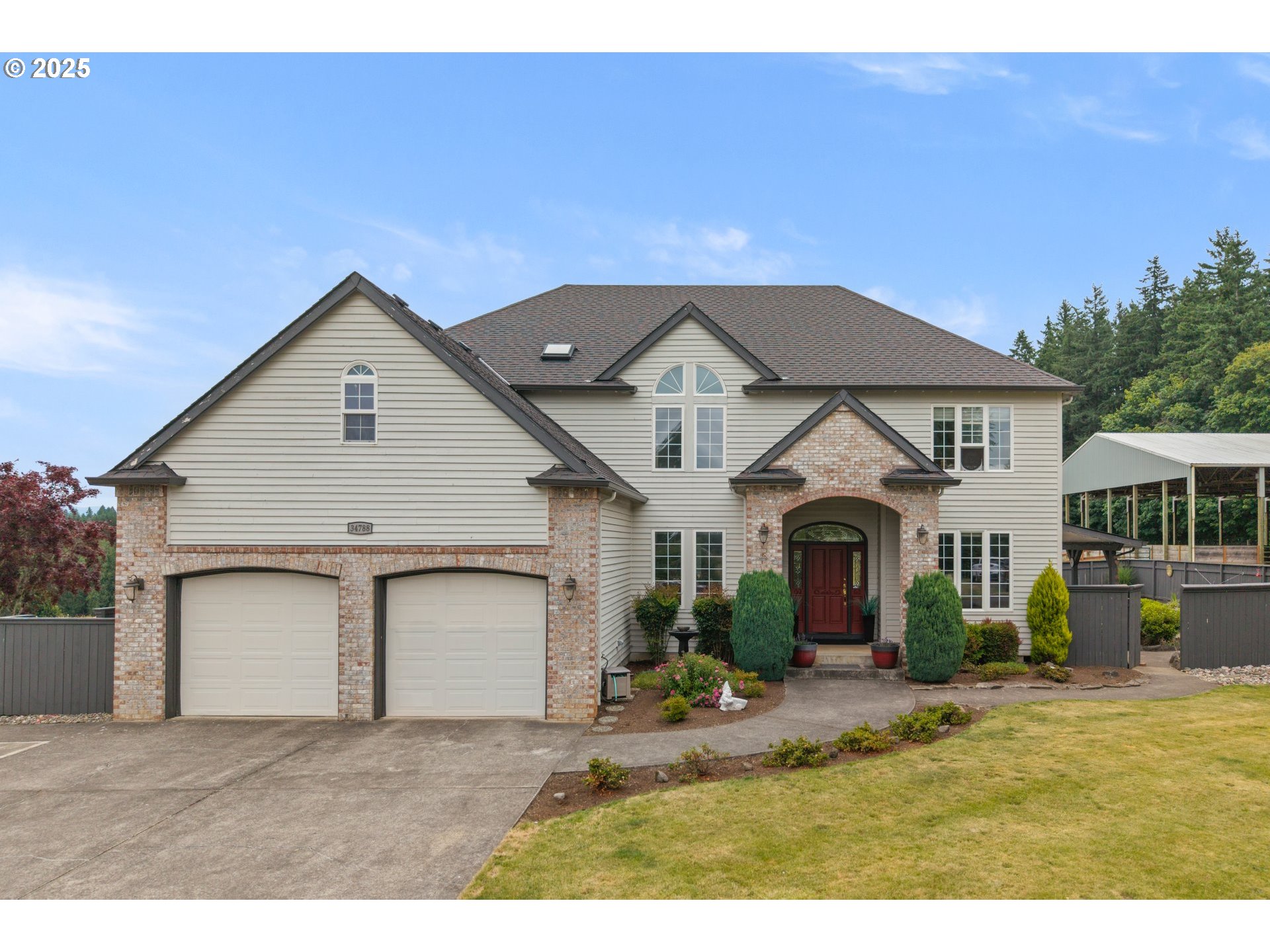 a view of a white house next to a yard with potted plants