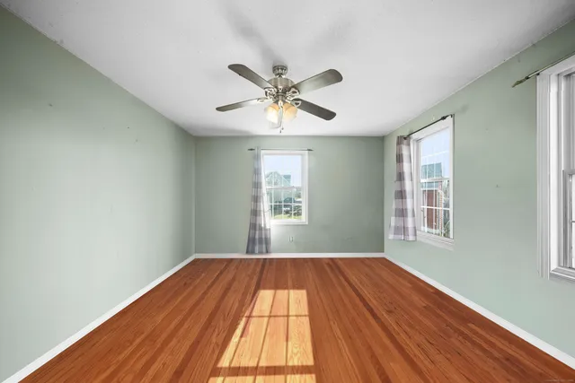 a view of an empty room with window and wooden floor