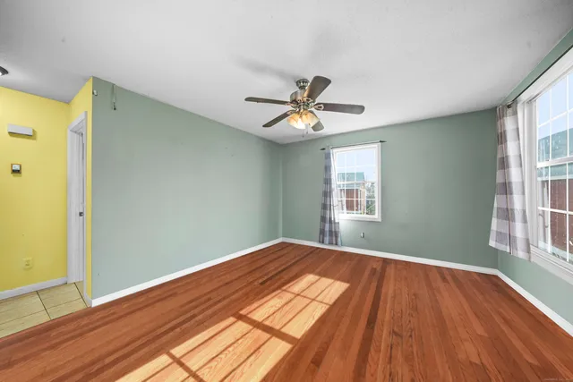 a view of empty room with wooden floor and fan