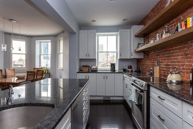 a kitchen with stainless steel appliances granite countertop a sink refrigerator and cabinets