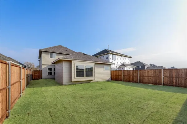 a white house with a yard plants and wooden fence
