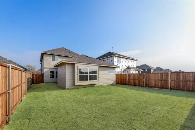 a white house with a yard plants and wooden fence