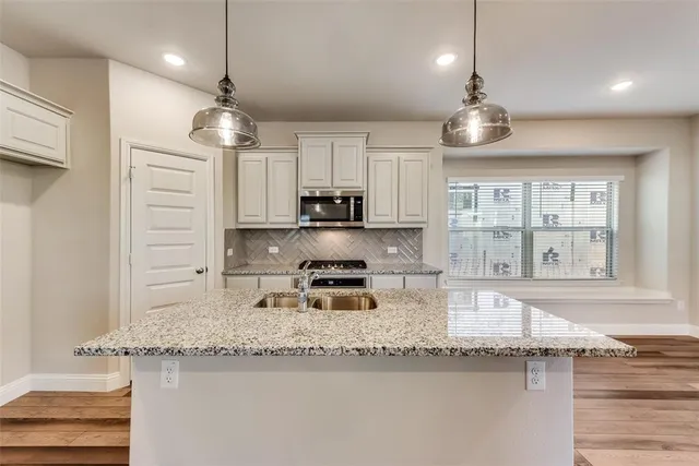 a kitchen with kitchen island granite countertop stainless steel appliances a sink and a counter top space