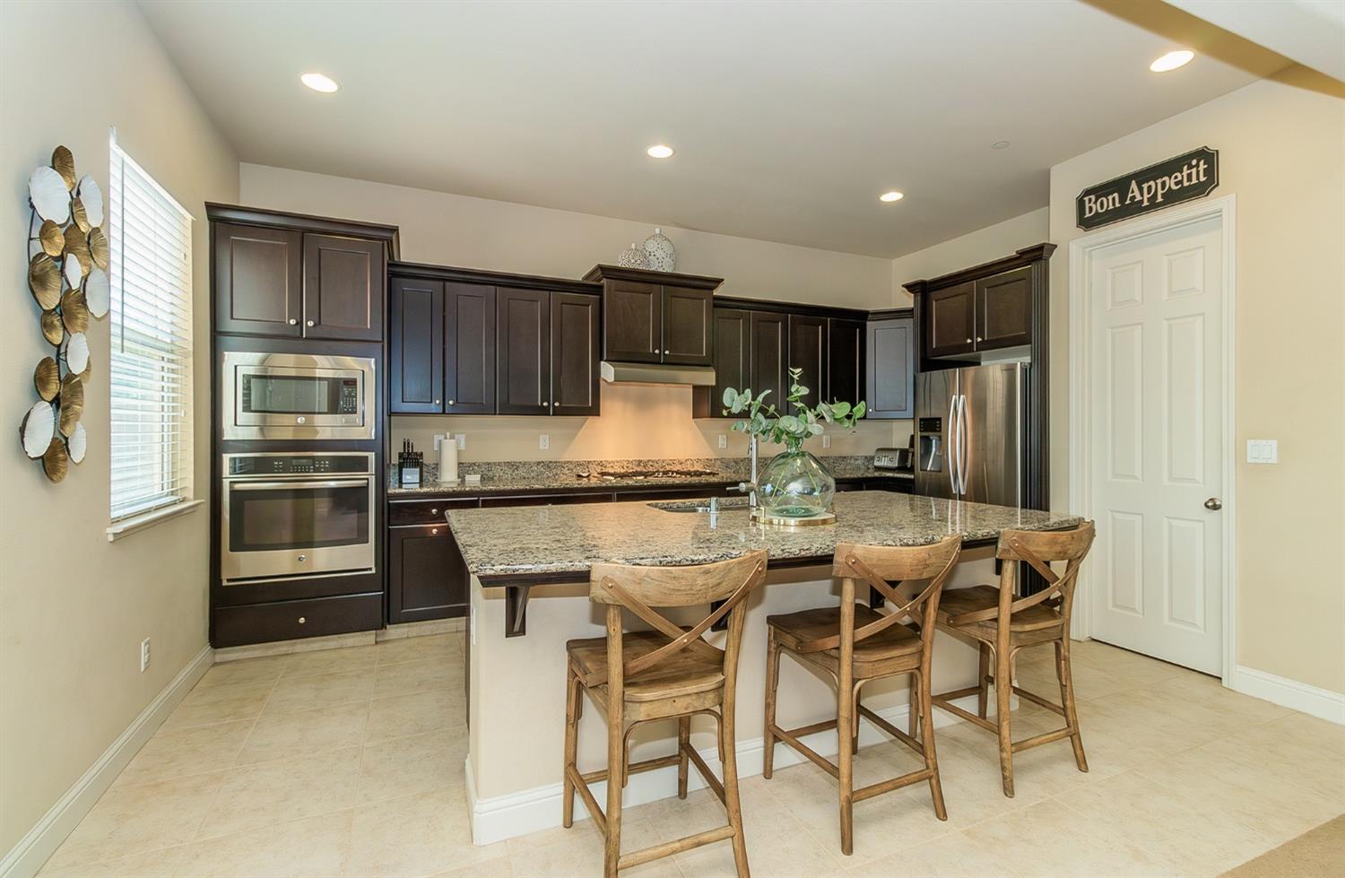 2610 Sample Avenue Clovis, CA 93611 - Photo 2 of 36 a kitchen with stainless steel appliances kitchen island granite countertop a refrigerator and cabinets