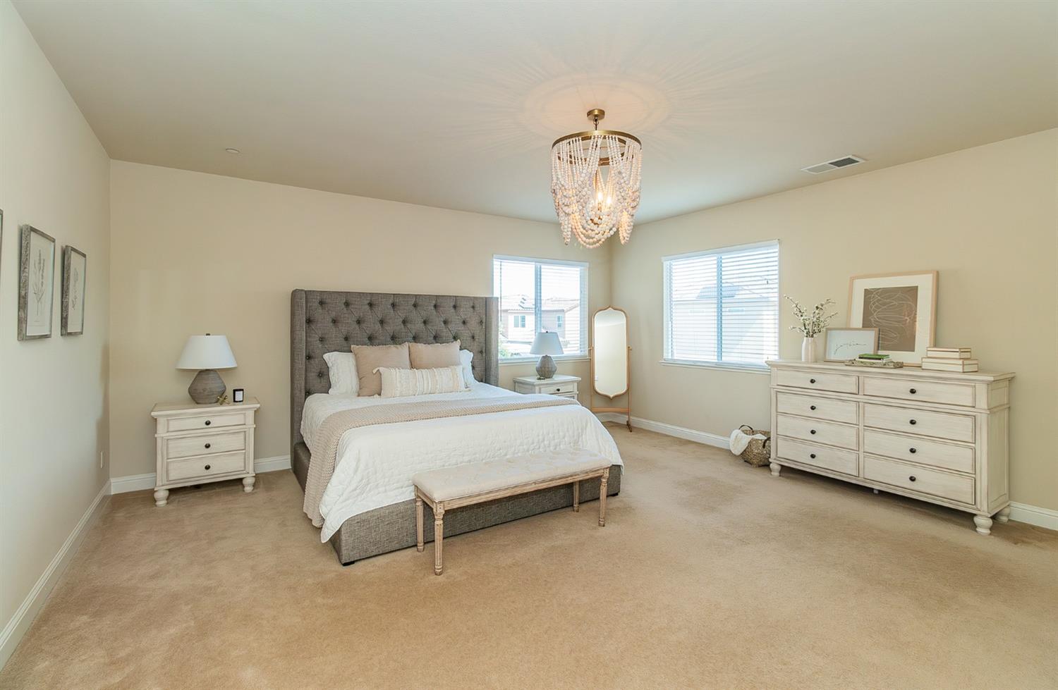 2610 Sample Avenue Clovis, CA 93611 - Photo 21 of 36 a spacious bedroom with a bed and a chandelier