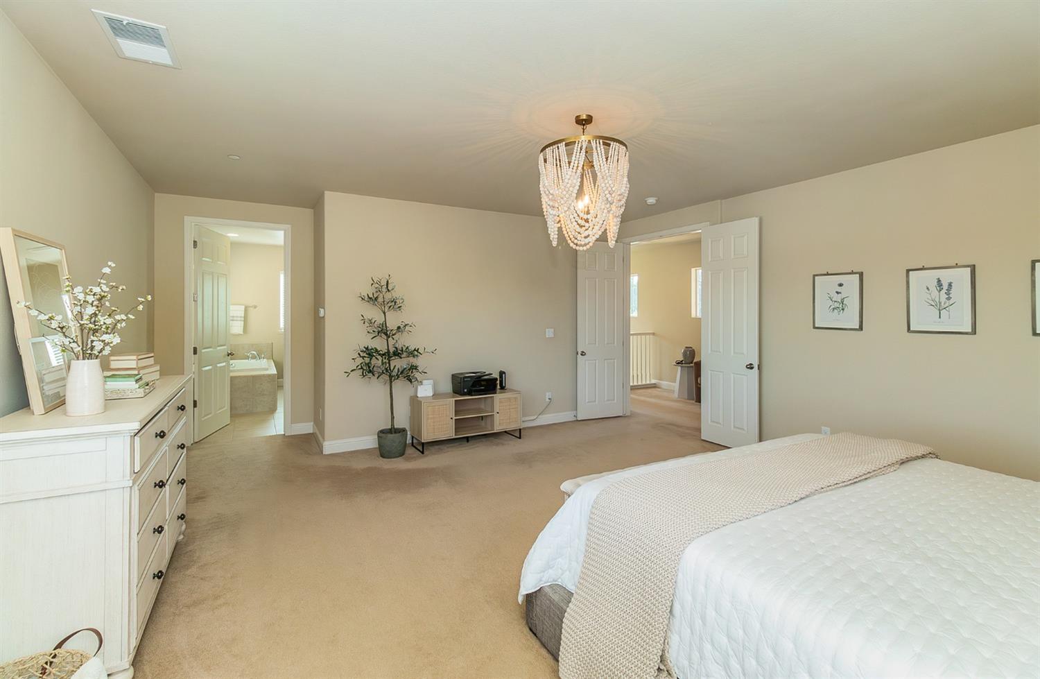 2610 Sample Avenue Clovis, CA 93611 - Photo 22 of 36 a spacious bedroom with a bed and a chandelier