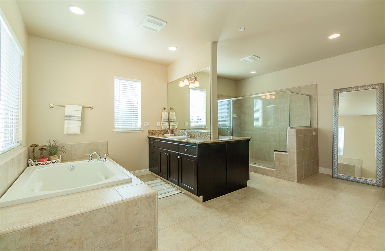 2610 Sample Avenue Clovis, CA 93611 - Photo 23 of 36 a bathroom with a tub sink and mirror