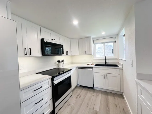 a kitchen with granite countertop white cabinets stainless steel appliances and a sink