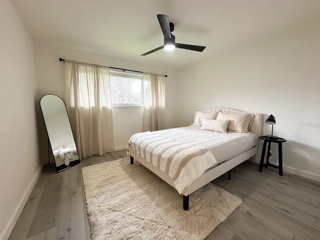 a bedroom with a bed a chair and a large window