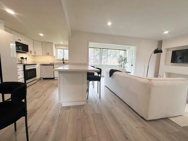 a living room with stainless steel appliances furniture large window and wooden floor
