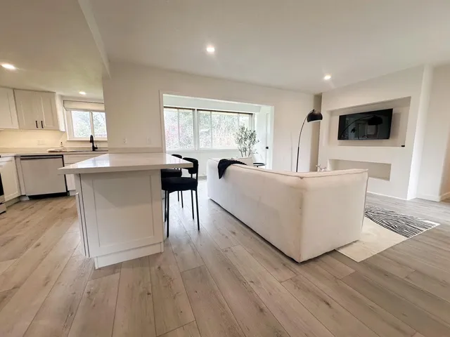 a living room with stainless steel appliances granite countertop furniture wooden floor and a window