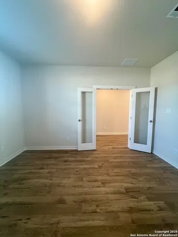 a view of an empty room with window and wooden floor