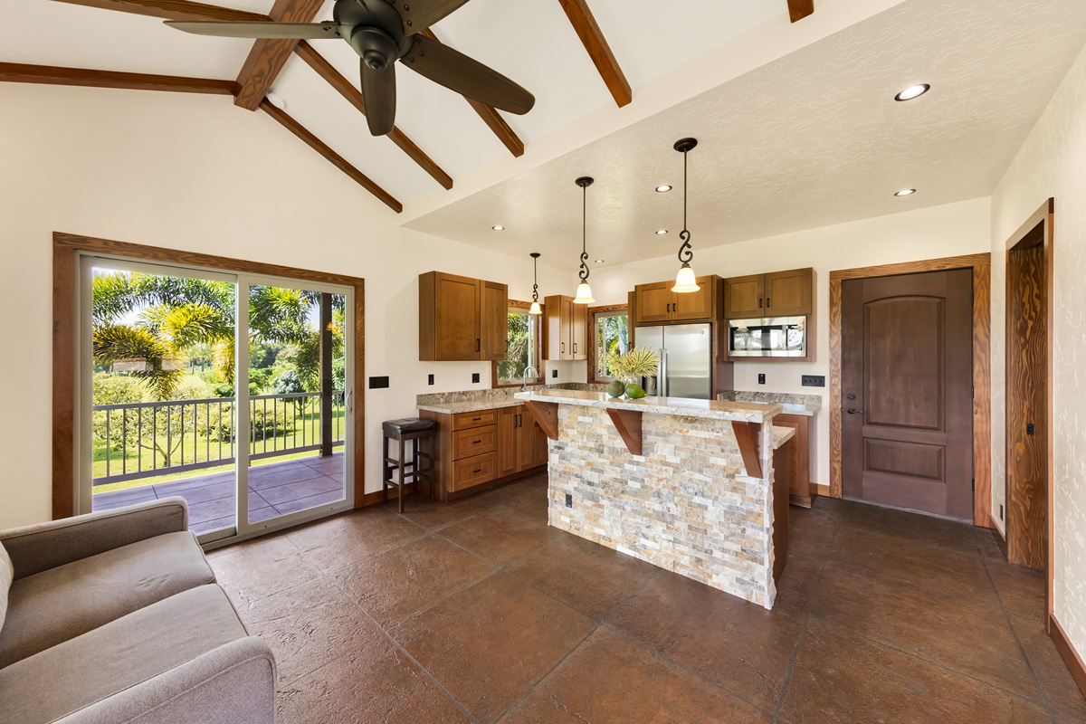 13-308 Kamaili Road Pahoa, HI 96778 - Photo 23 of 29 a large kitchen with stainless steel appliances kitchen island granite countertop a refrigerator a oven a sink and a dining table with the view