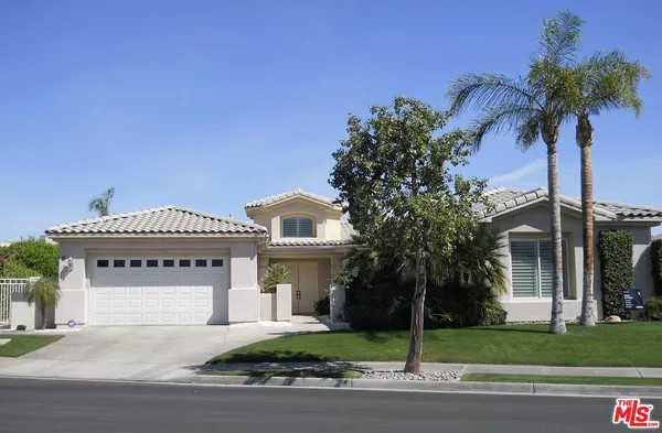 a front view of a house with a garden and palm trees