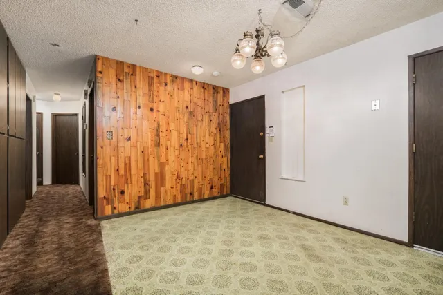 an empty room with chandelier fan and closet area