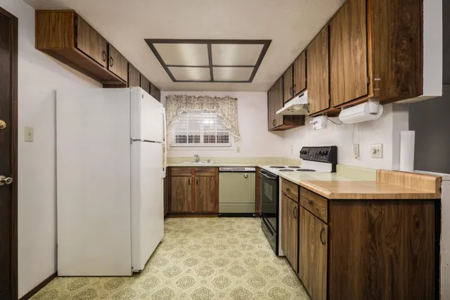 a kitchen with stainless steel appliances granite countertop a stove a sink dishwasher and a refrigerator with wooden cabinets
