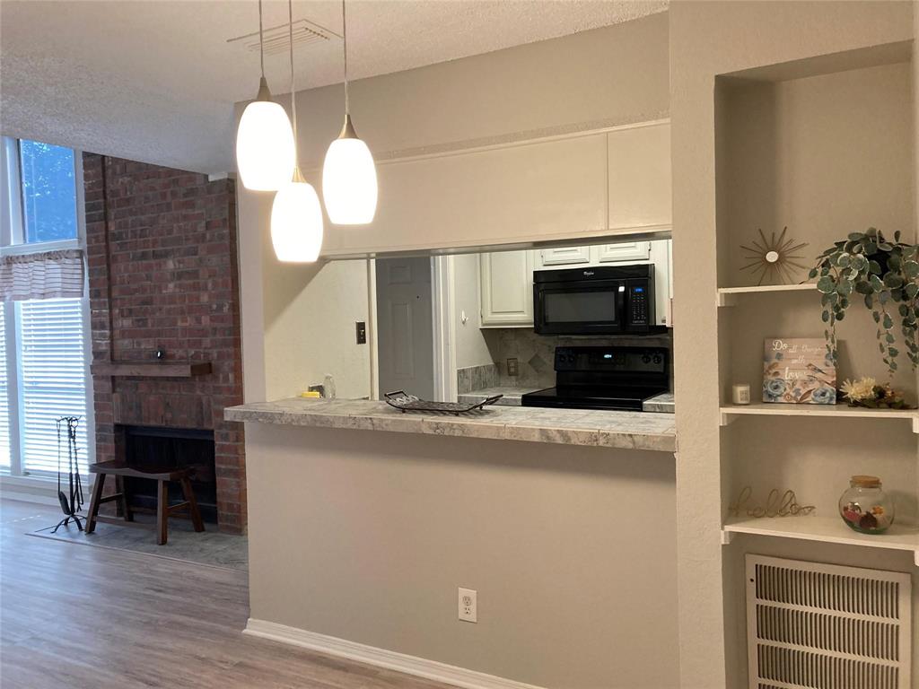 18240 Midway Road, Unit 905 Dallas, TX 75287 - Photo 5 of 15 Kitchen with black appliances, light countertops, decorative light fixtures, white cabinets, and light wood-type flooring