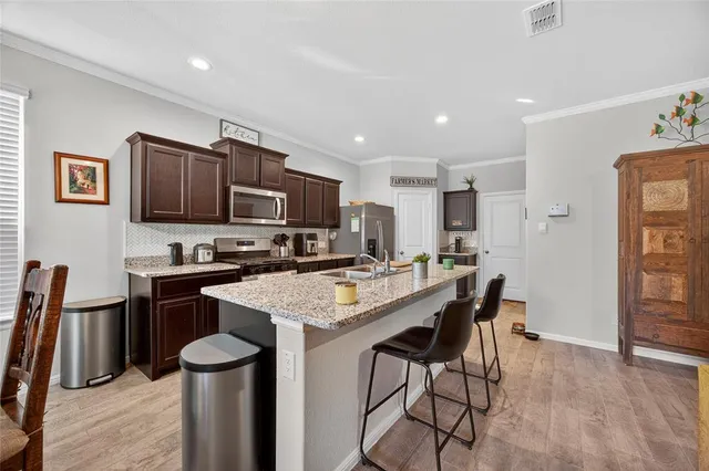 a kitchen with stainless steel appliances granite countertop a sink a stove a refrigerator cabinets and a dining table