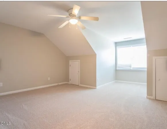 an empty room with chandelier fan and windows