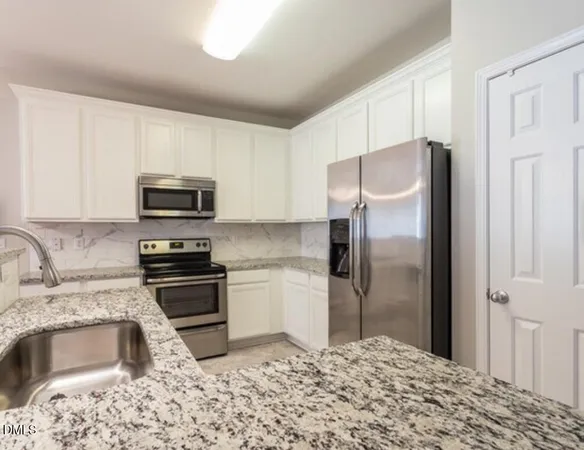 a kitchen with granite countertop a refrigerator stove and microwave
