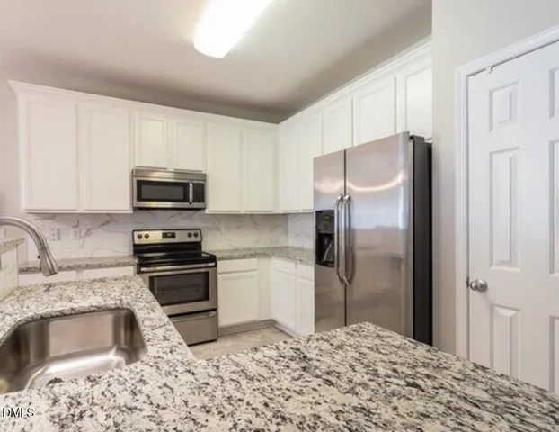 a kitchen with granite countertop a refrigerator stove and microwave