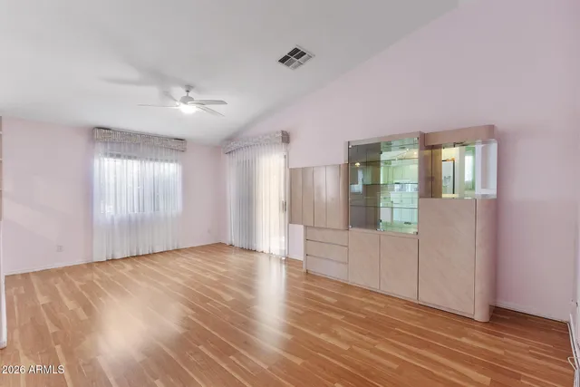 an empty room with wooden floor and windows