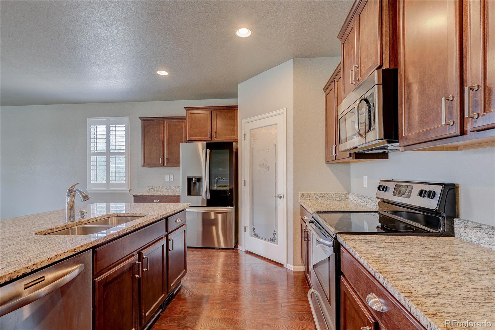 8891 Foxfire Street Firestone, CO 80504 - Photo 13 of 37 a kitchen with stainless steel appliances granite countertop a sink stove and refrigerator