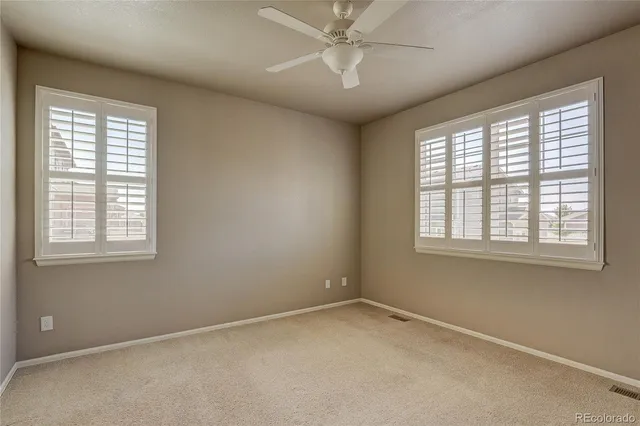 an empty room with a window and ceiling fan