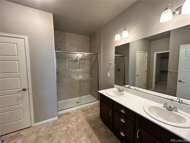 a bathroom with a double vanity sink mirror and shower