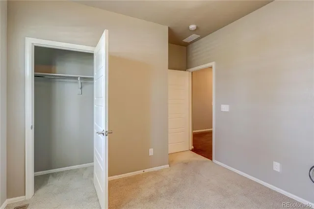 a view of an empty room with closet and wooden door