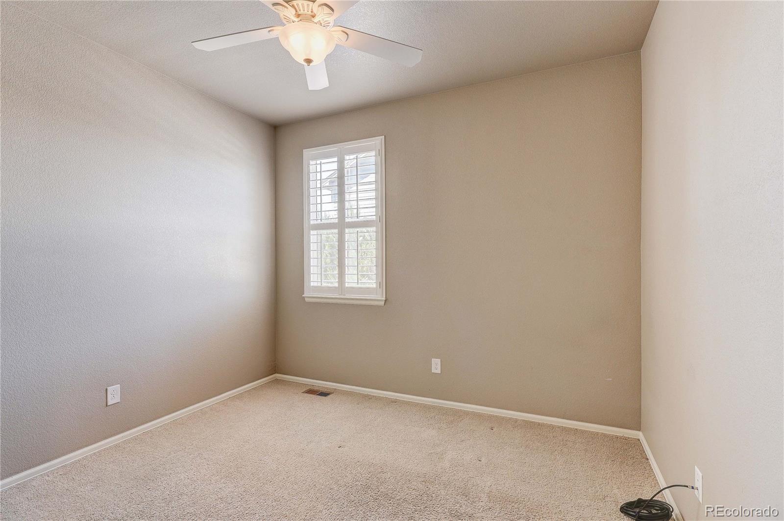 8891 Foxfire Street Firestone, CO 80504 - Photo 9 of 37 an empty room with a chandelier fan and windows