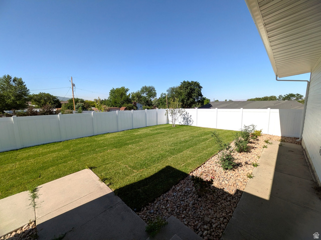 360 400 North Centerville, UT 84014 - Photo 8 of 30 Expansive backyard featuring a lush lawn, white privacy fencing, and a decorative rock border with small plantings