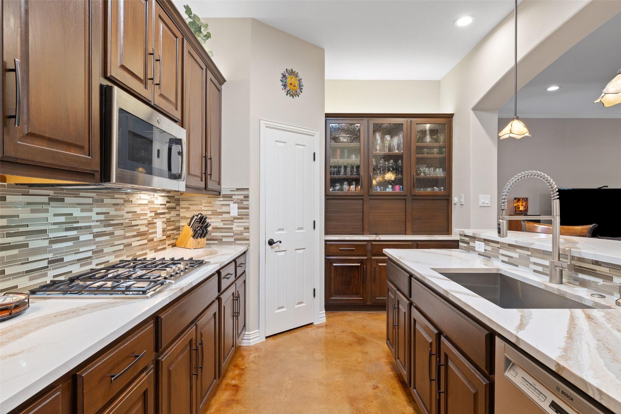 15208 Nightingale Lane Austin, TX 78734 - Photo 14 of 40 Kitchen with light stone countertops, glass fronted cabinets, tasteful backsplash, stainless steel appliances, and finished concrete flooring