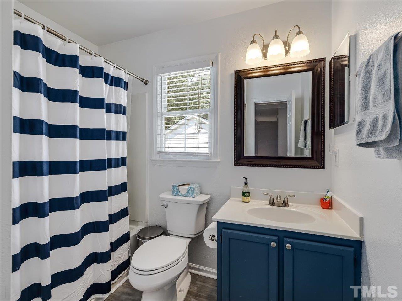11220 North Radner Way Raleigh, NC 27613 - Photo 19 of 24 a bathroom with a sink a toilet a mirror and shower curtain