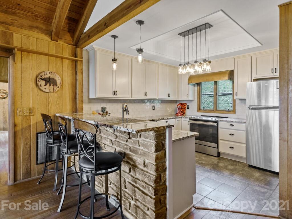 251 Riding High Road Waynesville, NC 28785 - Photo 11 of 41 a kitchen with stainless steel appliances a stove a refrigerator and a dining table with wooden floor