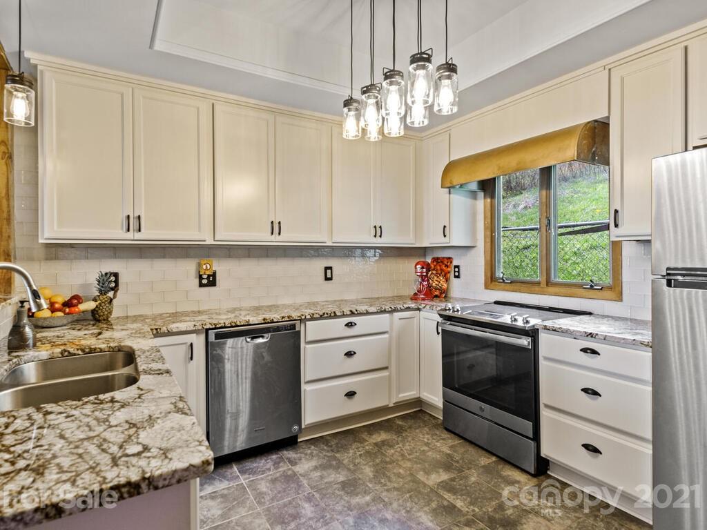 251 Riding High Road Waynesville, NC 28785 - Photo 10 of 41 a kitchen with stainless steel appliances granite countertop a stove a sink and a microwave