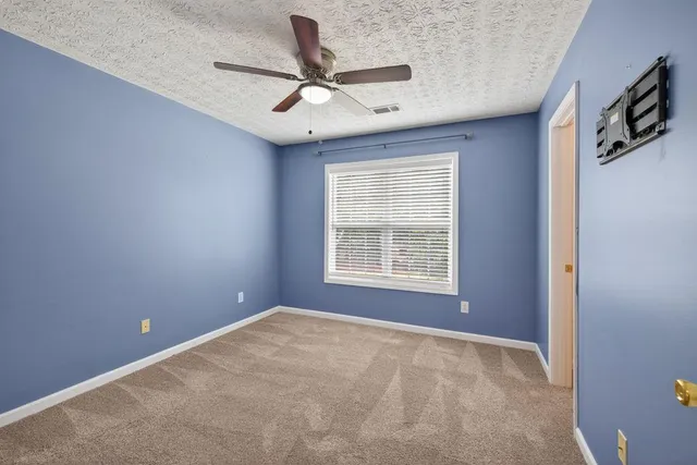 a view of a livingroom with a ceiling fan & windows