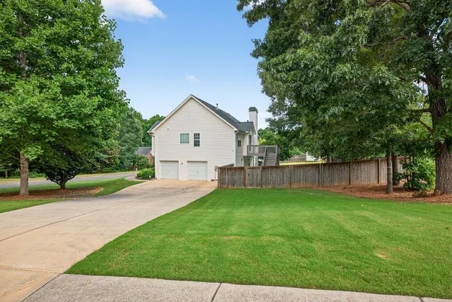 a view of a backyard with a house and large trees with wooden fence