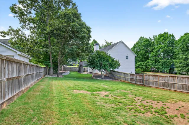 a view of a house with a yard and a large tree