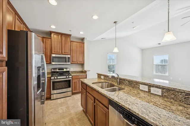 a kitchen with granite countertop stainless steel appliances a refrigerator a stove top oven and cabinets