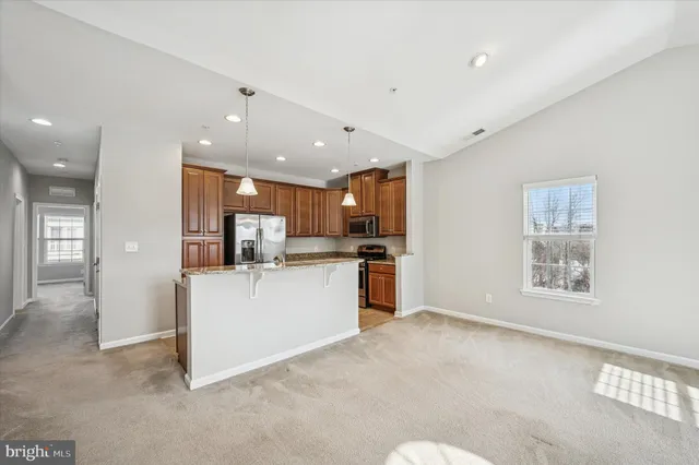 a kitchen with stainless steel appliances granite countertop a stove top oven a refrigerator and dishwasher with wooden floor