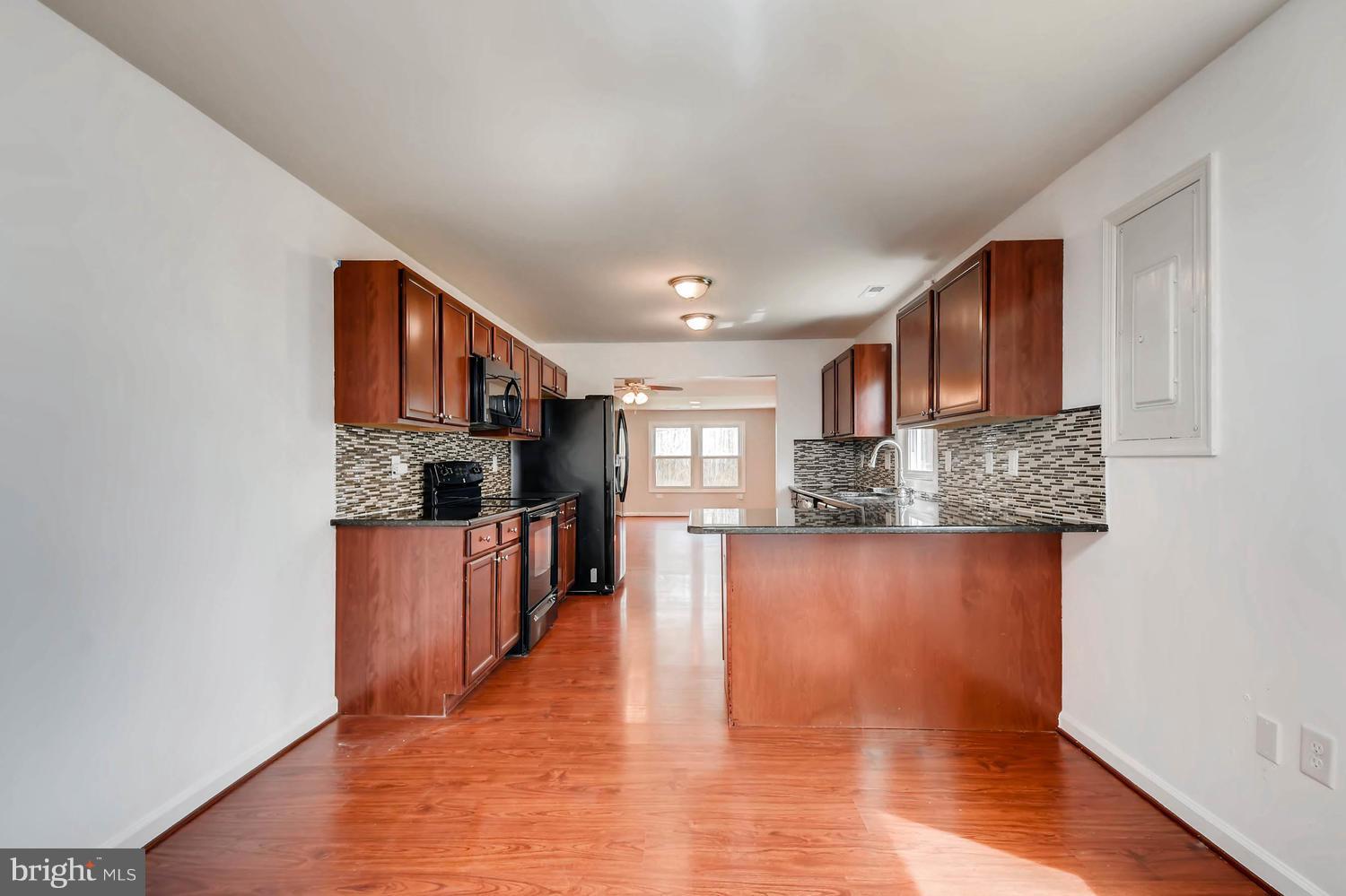 1468 Log Inn Road Annapolis, MD 21409 - Photo 6 of 28 a open kitchen with kitchen island granite countertop a refrigerator stove top oven and sink with wooden floor