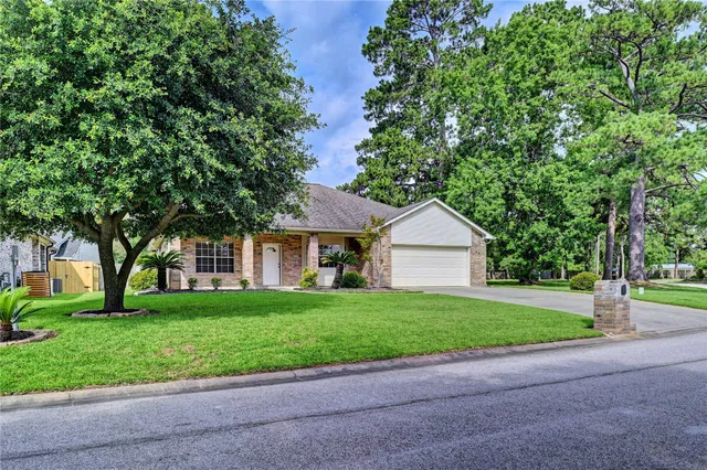 a front view of a house with a yard and large trees