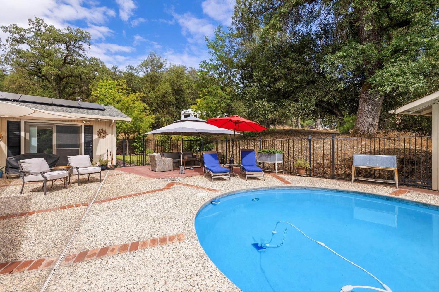 11460 Racetrack Road Sonora, CA 95370 - Photo 40 of 46 a view of a swimming pool with a table and chairs under an umbrella