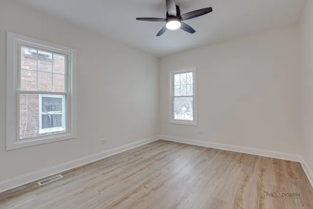 a view of empty room with wooden floor and fan